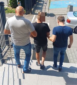Dwaj nieumundurowani policjanci prowadzą zatrzymanego.