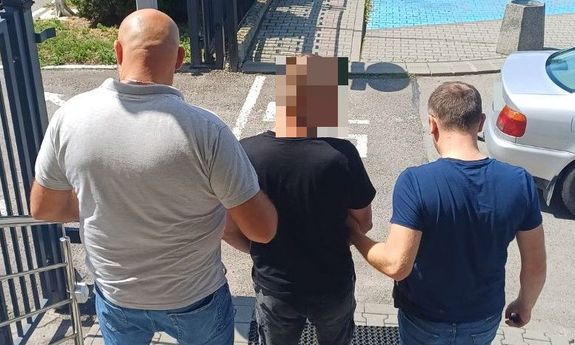 Dwaj nieumundurowani policjanci prowadzą zatrzymanego.