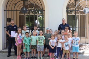 Dwaj policjanci pozują do zdjęcia z grupą dzieci.