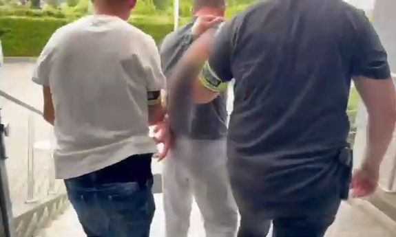 Dwaj policjanci prowadzą zatrzymanego.