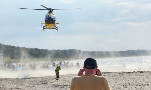 Śmigłowiec na plażą. W głębi duża grupa osób.
