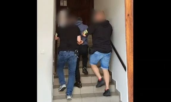 Dwaj policjanci prowadzą zatrzymanego.