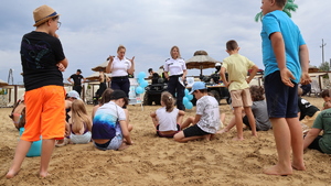 Policjantki na plaży rozmawiają o bezpieczeństwie z grupą dzieci.