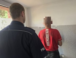 policjant stoi przed zatrzymanym.