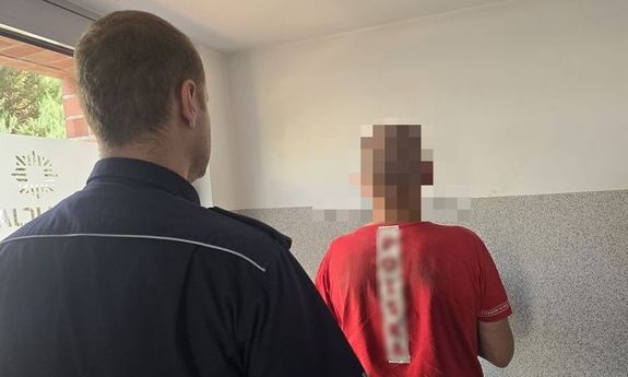 policjant stoi przed zatrzymanym.