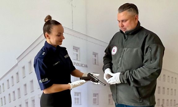 Mężczyzna i policjantka. Kobieta trzyma w ręku broń.