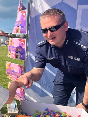 Policjant witający się z osobą niewidoczną w kadrze zdjęcia.