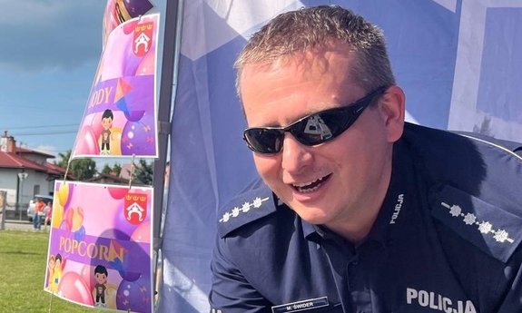 Policjant witający się z osobą niewidoczną w kadrze zdjęcia.