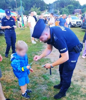Policjanci rozdają ulotki promujące bezpieczne zachowania podczas letniego wypoczynku.