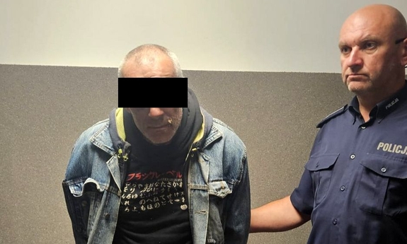 Zatrzymany mężczyzna trzymany przez policjanta.