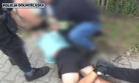 Policjanci zakuwają na ziemi zatrzymanego.