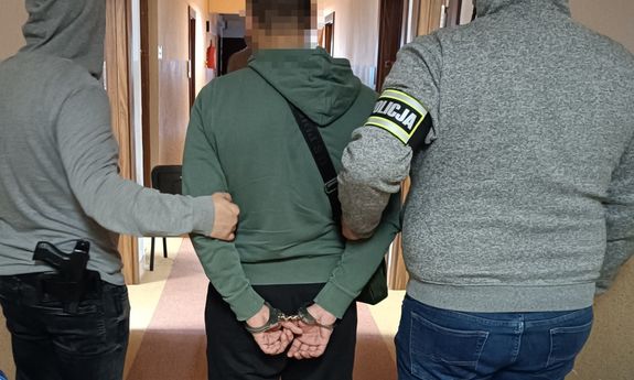 Dwaj policjanci prowadzą zatrzymanego.