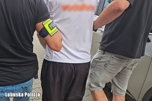 Dwaj funkcjonariusze prowadzą zatrzymanego.