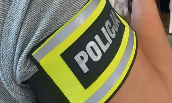 Napis policja na opasce umieszczonej na ręce.