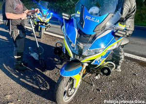 Hulajnoga przy motorze policyjnym.