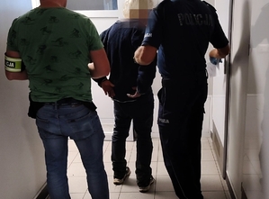 Mężczyzna prowadzony przez dwóch policjantów.