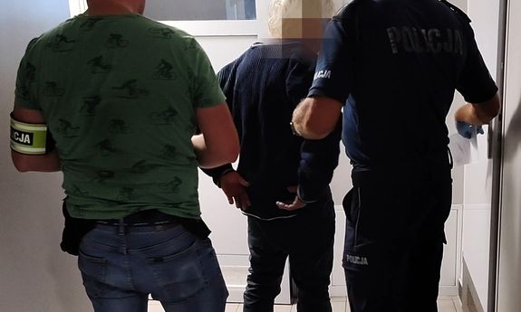 Mężczyzna prowadzony przez dwóch policjantów.