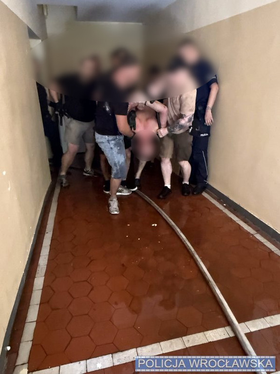 Zatrzymany mężczyzna prowadzony przez policjantów.