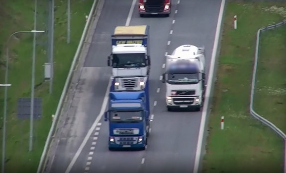 Stop klatka z nagrania, na którym jadący ciężarówkami wyprzedzają się wzajemnie.
