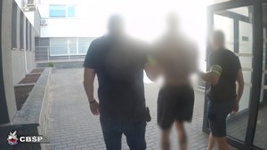 Dwaj policjanci prowadzą zatrzymanego.
