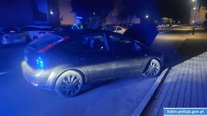 Pora nocna. Samochód z otwarta maska na jezdni, a przy nim policjant.