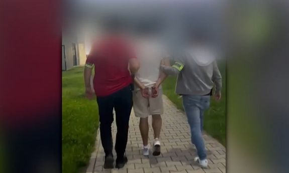 Dwaj policjanci prowadzą zatrzymanego.