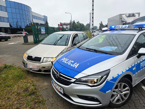 Radiowóz policyjny stoi obok zatrzymanego samochodu.