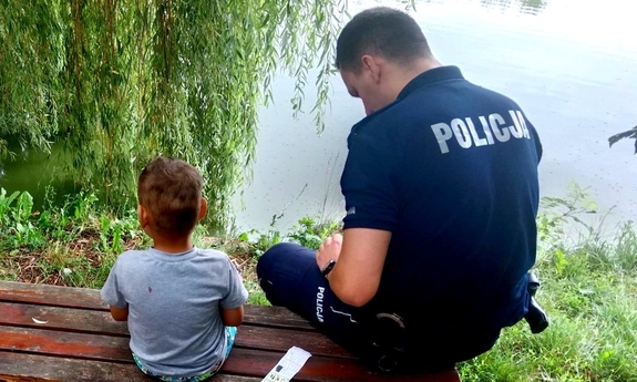 Policjant siedzący na ławce z dzieckiem.