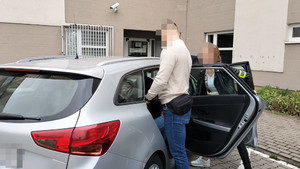 Funkcjonariusz prowadzi zatrzymanego mężczyznę.