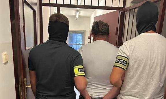 Dwaj funkcjonariusze prowadzą zatrzymanego.