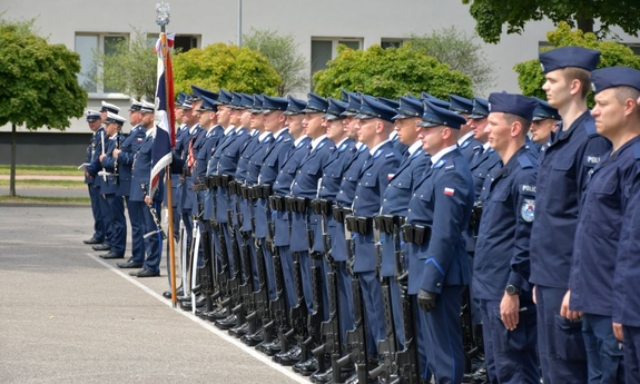 Grupa policjantów stoi w szeregu na placu w trakcie uroczystości.