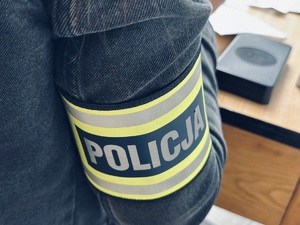 Opaska z napisem Policja na ramieniu funkcjonariusza.
