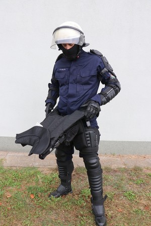 Zdjęcie przedstawia funkcjonariusza Policji w zestawie przeciwuderzeniowym z kamizelką OPP-4K