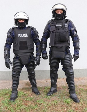 Zdjęcie przedstawia dwóch funkcjonariuszy Policji w zestawach przeciwuderzeniowych z kamizelką OPP-4K