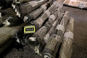 Zwinięte i zafoliowane dywany leżą jeden na drugim.