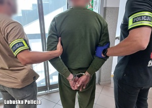 Dwaj policjanci prowadzą zatrzymanego.
