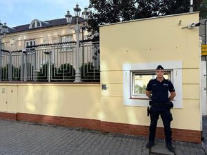Policjant stoi przed budynkiem.