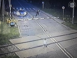 Na zdjęciu widać torowisko a na nim kucającego chłopca. Za rogatkami policyjny radiowóz i biegnący w kierunku dziecka policjant.