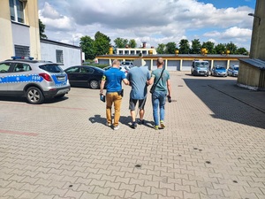 Policjanci prowadzą zatrzymanego mężczyznę.