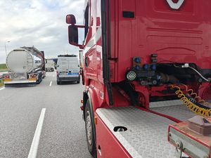 Kabina samochodu ciężarowego widziana od tyłu. W głębi radiowóz i inne pojazdy.