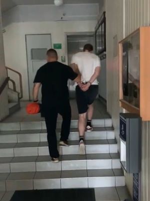 policjant idzie z zatrzymanym po schodach.