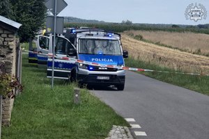 Zdjęcie przedstawia policyjne radiowozy ustawione przy drodze.