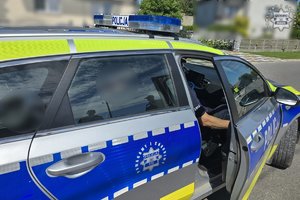Zdjęcie przedstawia radiowóz wewnątrz, którego siedzi zatrzymany.