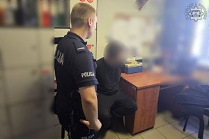 Zdjęcie przedstawia policjanta stojącego obok zatrzymanego.