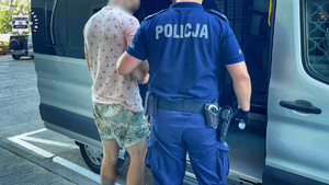 Policjant prowadzi zatrzymanego.