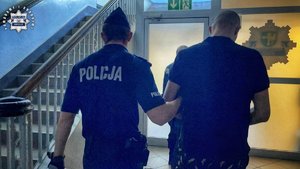 Policjant prowadzi zatrzymanego.