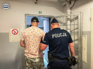 Policjant prowadzi zatrzymanego.