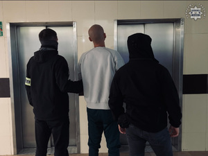 Dwaj policjanci prowadzą zatrzymanego.