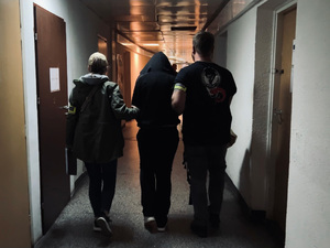 Dwaj policjanci prowadzą zatrzymaną.