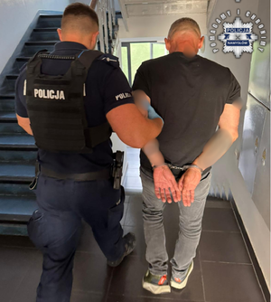 Policjant prowadzi zatrzymanego.